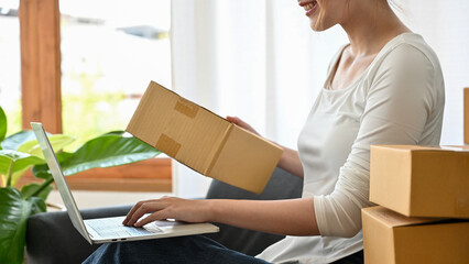 Cropped image, woman using laptop computer and preparing her shipping package