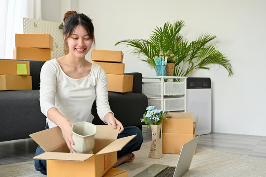 Female online business owner enjoy packing her products into a parcel box.