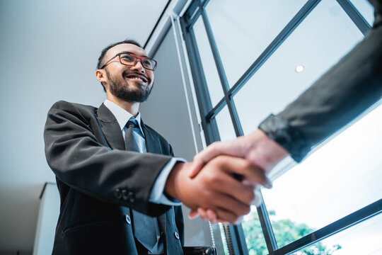 Close Up Portrait Of Asian Businessmen Shaking Hands And Smiling Shot From Below