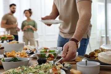 Man taking slice of pizza from buffet indoors, closeup. Brunch table setting