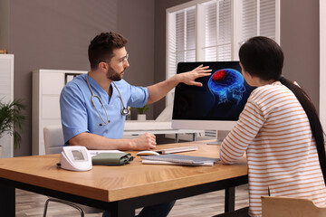 Neurologist showing brain scan to young woman in clinic