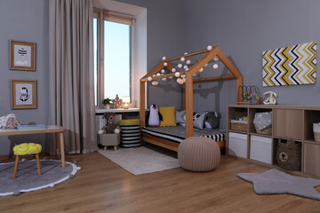 Stylish child room interior with comfortable house bed and toys