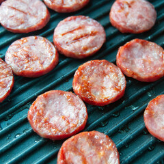 grilled sausage slices. sausages on a grill pan. picnic. fat meat. Preparation of semi-finished products. Square image.