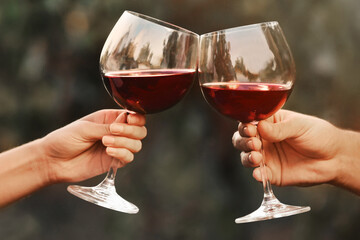 Couple with glasses of red wine outdoors, closeup