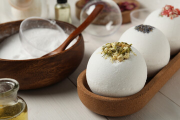 Different bath bombs and ingredients on white wooden table, closeup