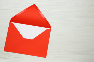 Envelope with blank paper card on white wooden table, top view. Space for text