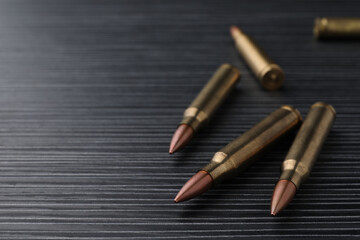 Many bullets on black wooden table, closeup. Space for text