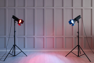 Bright red and blue spotlights near wall indoors, space for text