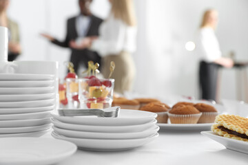 Table with different delicious snacks and dishware indoors. Coffee break