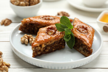 Delicious sweet baklava with walnuts and mint on white wooden table, closeup