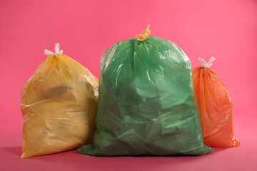 Trash bags full of garbage on pink background