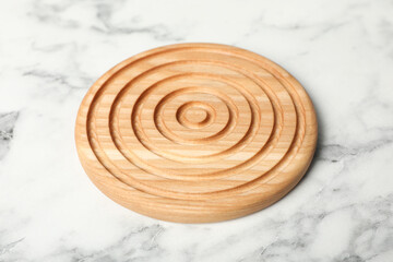 Stylish wooden cup coaster on white marble table, closeup