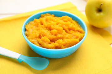 Plastic dishware with healthy baby food on white table, closeup