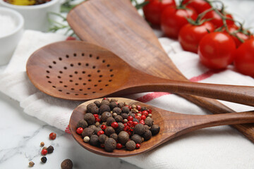 Composition with wooden cooking utensils and peppercorns on white marble table, closeup