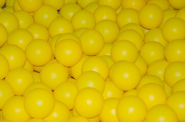texture of plastic balls for children. Background of yellow balloons. Pile of toy balls for dry pool