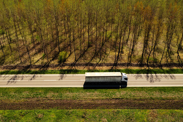 Fototapeta High angle view aerial shot of semi-truck on highway with wooded landscape in background obraz