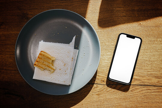 Smartphone and toasted bread on the plate in kitchen