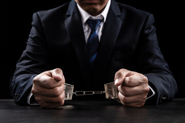 A man in a blue business suit holding hands in handcuffs