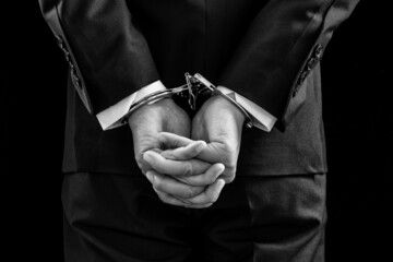 Businessman and his hands on the back handcuffed.Black and white