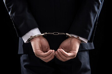 Businessman and his hands on the back handcuffed