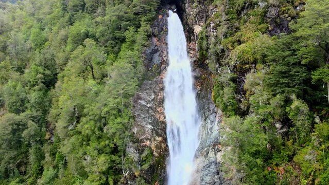 Aerial orbit of the Rio Blanco waterfall surrounded by the forest of Hornopiren National Park, Chile.