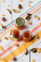 jam in several jars on a striped light-colored fabric decorated with dry leaves flat lay
