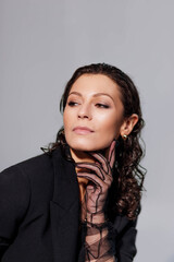 stylish brunette woman with curly hair styling in lacy black gloves posing, boudoir image of beautiful woman in studio.
