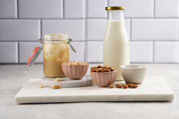 Fototapeta na wymiar Peanuts, almonds in pink bowls, homemade peanut butter and almond milk on marble boards. Vegan food