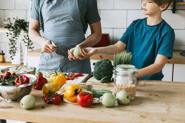 family dad young man and son teenage boy cook vegetable salad in kitchen and spend quality time together, father and son talking and cooking vegetarian food and doing chores, 8 march and mothers day