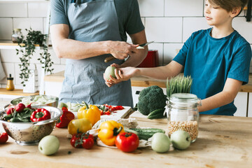 family dad young man and son teenage boy cook vegetable salad in kitchen and spend quality time together, father and son talking and cooking vegetarian food and doing chores, 8 march and mothers day