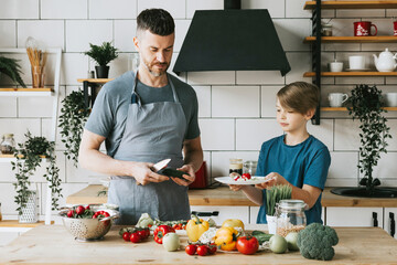 family dad young man and son teenage boy cook vegetable salad in kitchen and spend quality time together, father and son talking and cooking vegetarian food and doing chores, 8 march and mothers day
