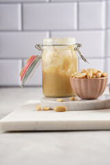 Peanuts in pink bowls, homemade peanut butter in mason jar on marble boards