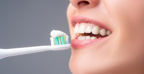 Close-up mouth with teeth-brush. Dental health care clinic. Close-up of a young woman is brushing her teeth. Toothbrush with toothpaste. Dental banner, copyspace.
