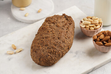 Homemade gluten-free and yeast-free buckwheat whole bread bread loaf with sunflower and pumkin seeds and nuts on white marble board