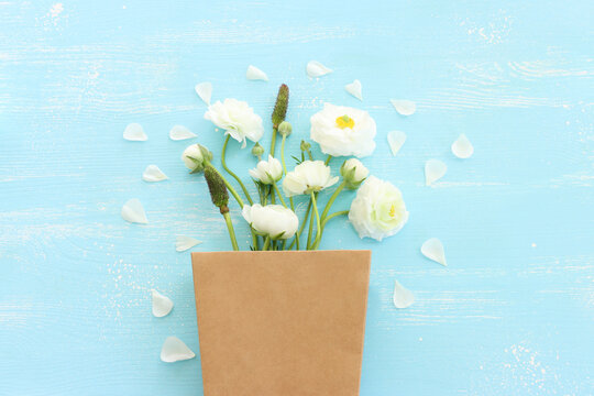 Top view image of white flowers composition over wooden blue pastel background