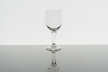 Empty wine glass with reflection on background, front view
