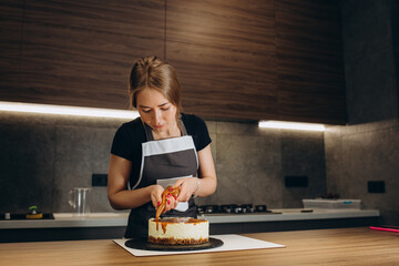 Confectioner at work. Cream cake decorating. Cook table preparing a cake on a gray background.