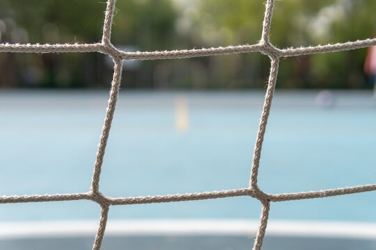 Nets of a soccer goal with background blur and a person shooting at goal. Image of the nets in the background of a goal on the blue football fields.