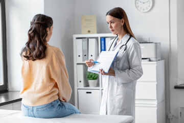 medicine, healthcare and people concept - female doctor or cardiologist with clipboard showing...