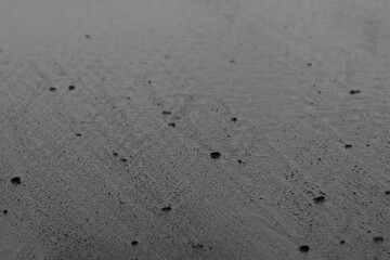 Fototapeta na wymiar Wet black volcanic sand on seashore, texture, background.