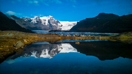 Glaciers and mountains reflected in lake with blue sky