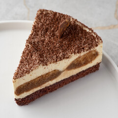 Tiramisu, traditional Italian dessert on a white plate. Close up.