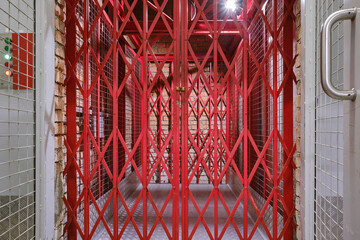 Red latticed freight elevator doors. Factory elevator gate. Self storage facility, red metal doors. Moving, organizing, storage concept. Selective focus © VLAD ANTONOV