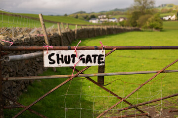 Shut Gate sign handwritten in blue paint on old wood