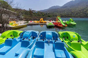 Group of colorful pedal boats next to the wooden pier of Lake Kournas, Crete. Active rest outdoor