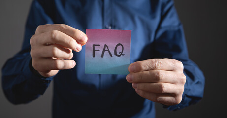 Man showing FAQ on sticky note.