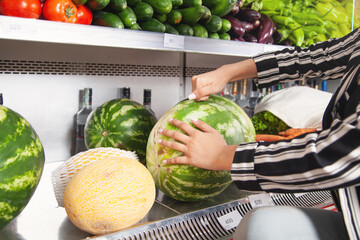  Woman buying watermelon in food store.