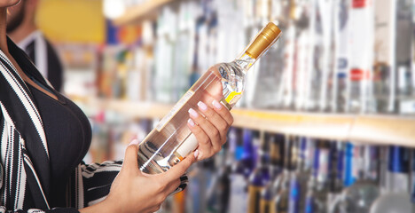 Woman buying vodka at supermarket.