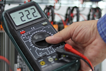 A multimeter in the hands of an engineer with the parameters of the voltage of the electric current...