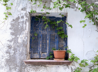 Old blue wooden window shutters of a mediterranean house, vintage background.